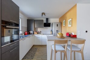 Une cuisine moderne dotée d’un îlot central, d’appareils électroménagers intégrés et d’un coin repas avec des chaises.