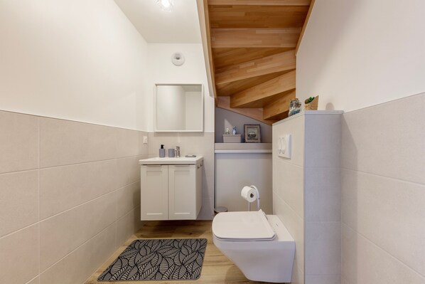 Une petite salle de bain comprenant des toilettes, un lavabo et un miroir.