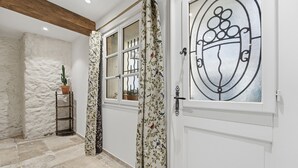 A room with a white door, a window with a metal grill, a potted plant, and a textured wall. - Robin's Nest – Cocon au cœur du Vieil Antibes (Antibes)