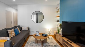 Een moderne woonkamer met een bank, een salontafel, een televisie en een spiegel aan de muur.