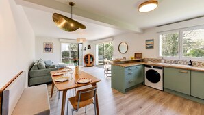 A modern kitchen with a dining area, a sofa, and a washing machine. - So Dune - La Teste 5km de la Plage (La Teste-de-Buch)