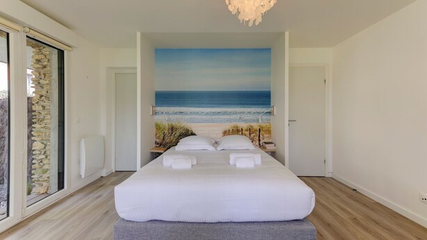 A bedroom with a large bed, a view of the sea through a window, and a modern chandelier. - So Dune - La Teste 5km de la Plage (La Teste-de-Buch)