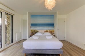 Una camera da letto con un letto grande, vista mare attraverso una finestra e un lampadario moderno.