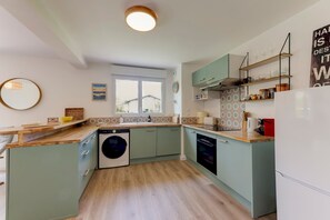 Eine kompakte Küche mit Waschmaschine, Backofen und Kühlschrank.