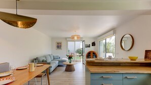 A modern kitchen with a wooden dining table, a sofa, and a large window. - So Dune - La Teste 5km de la Plage (La Teste-de-Buch)