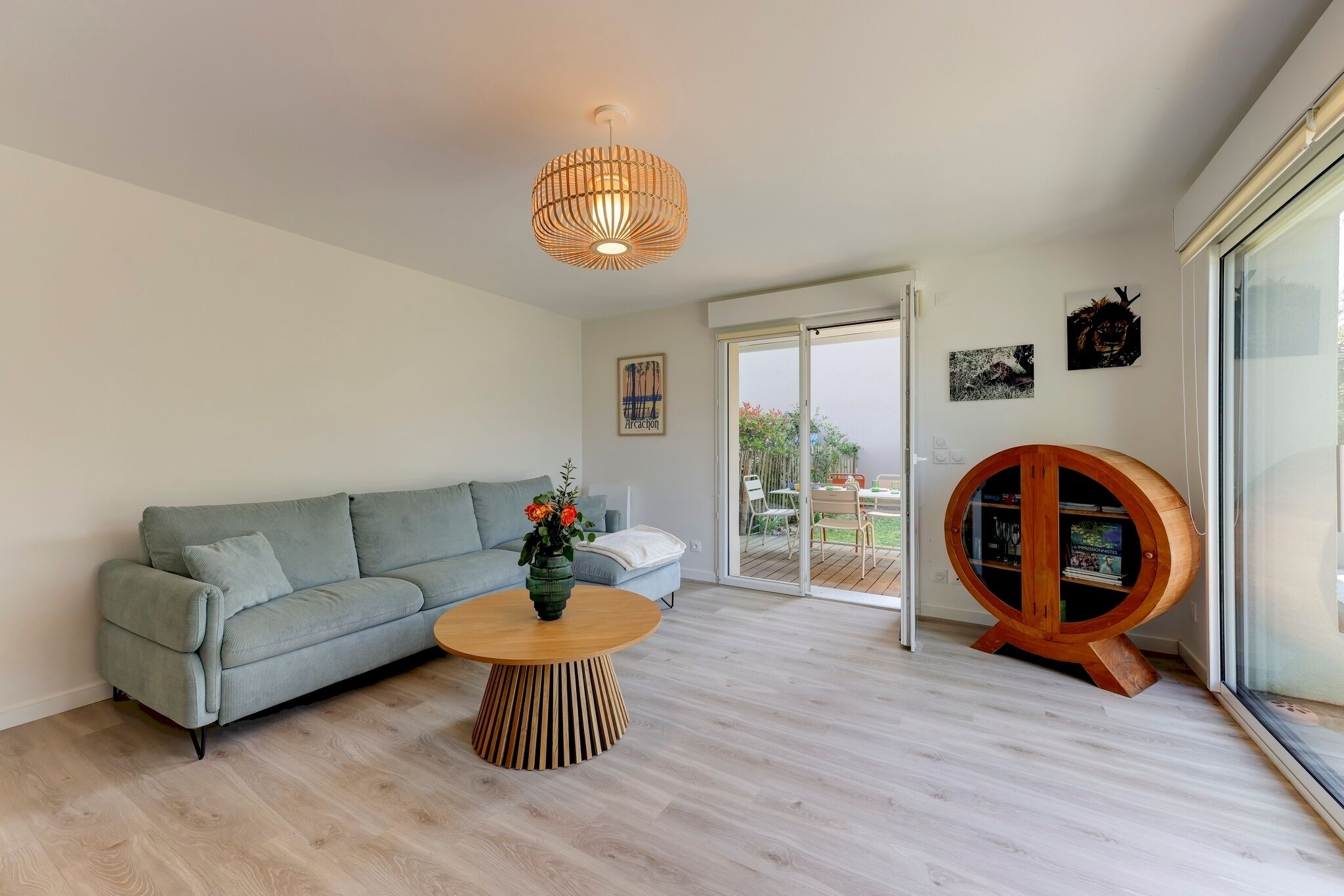 Una sala de estar moderna con un sofá gris, una mesa de centro de madera, un colgante de luz y un mueble de madera.