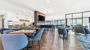 A modern hotel lobby with a large seating area, a kitchen in the background, and large windows offering views. - Sleep Inn & Suites Savannah Tennessee Riverfront (Savannah)