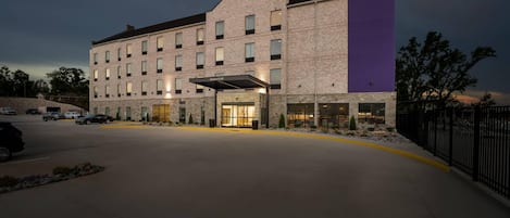 Un hotel con fachada de ladrillo, un llamativo letrero de Sleep Inn & Suites y una entrada cubierta.