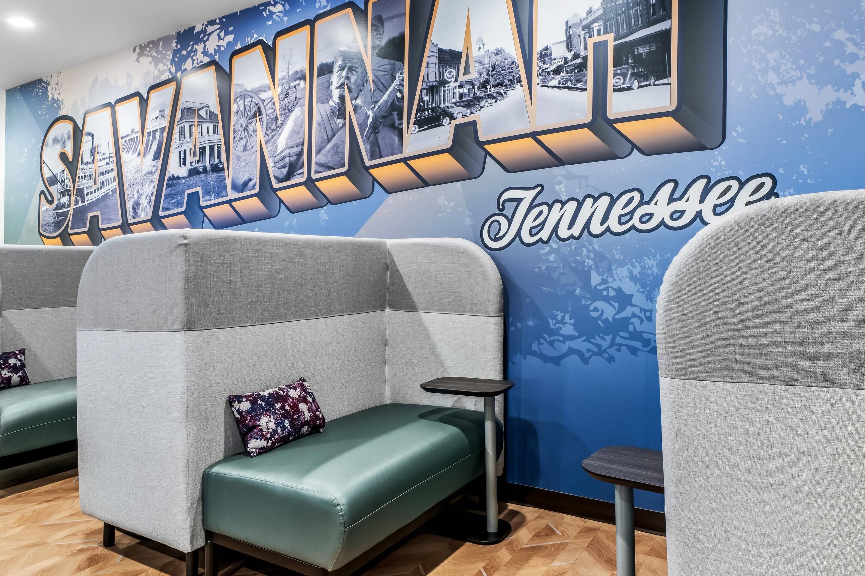 A seating area with cushioned benches, a small table, and a wall with a large 'SAVANNAH' sign.