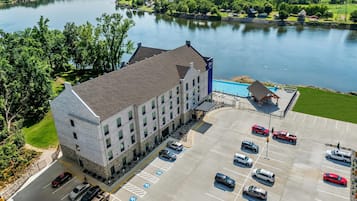 A hotel with a parking lot, a swimming pool, and a view of a lake.