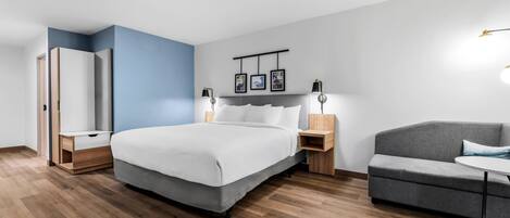 A modern bedroom with a bed, bedside tables, a wardrobe, a sofa, and a small table.
