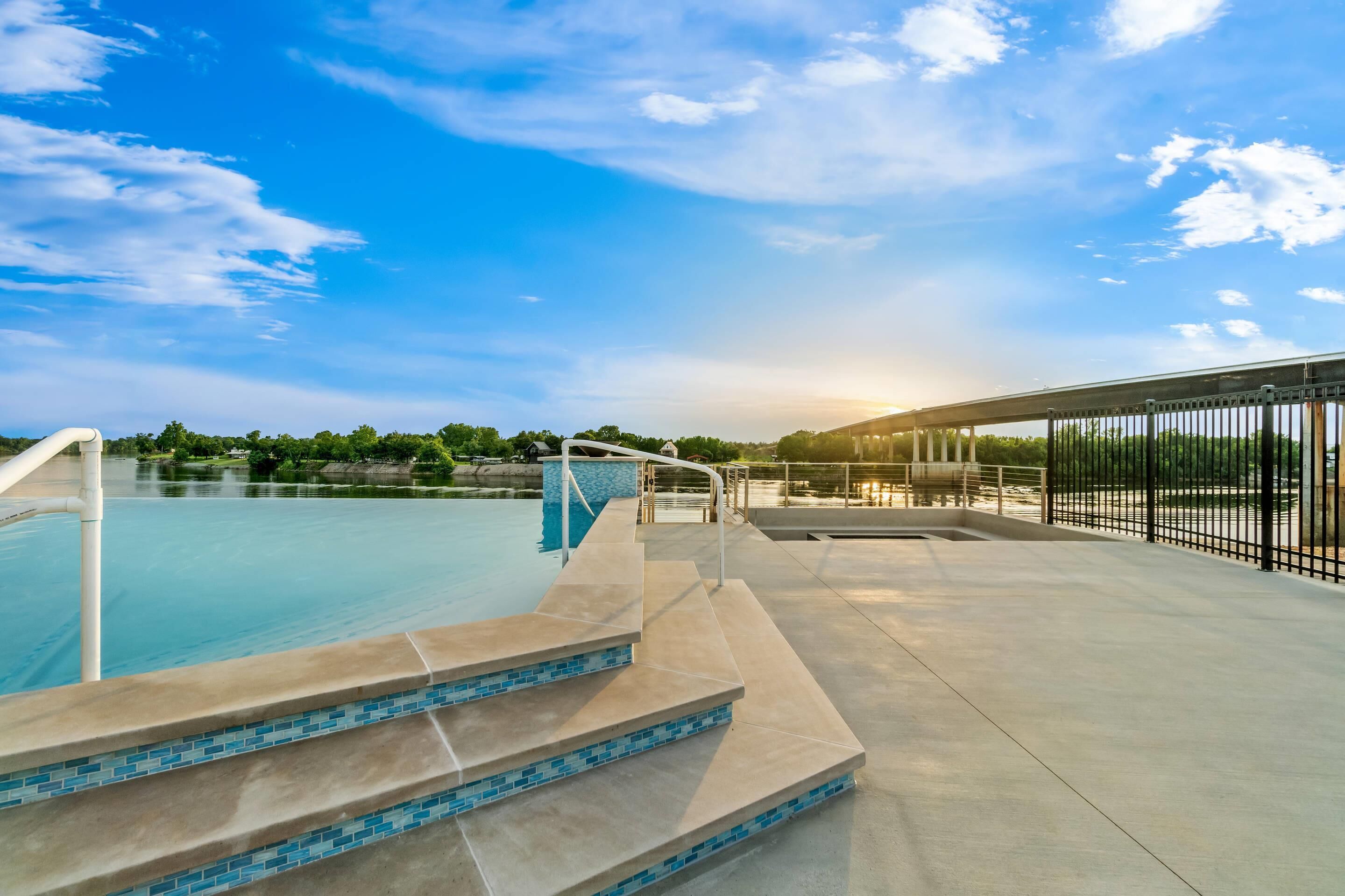 A swimming pool with steps leading into it, a clear sky, and a distant view of a bridge.