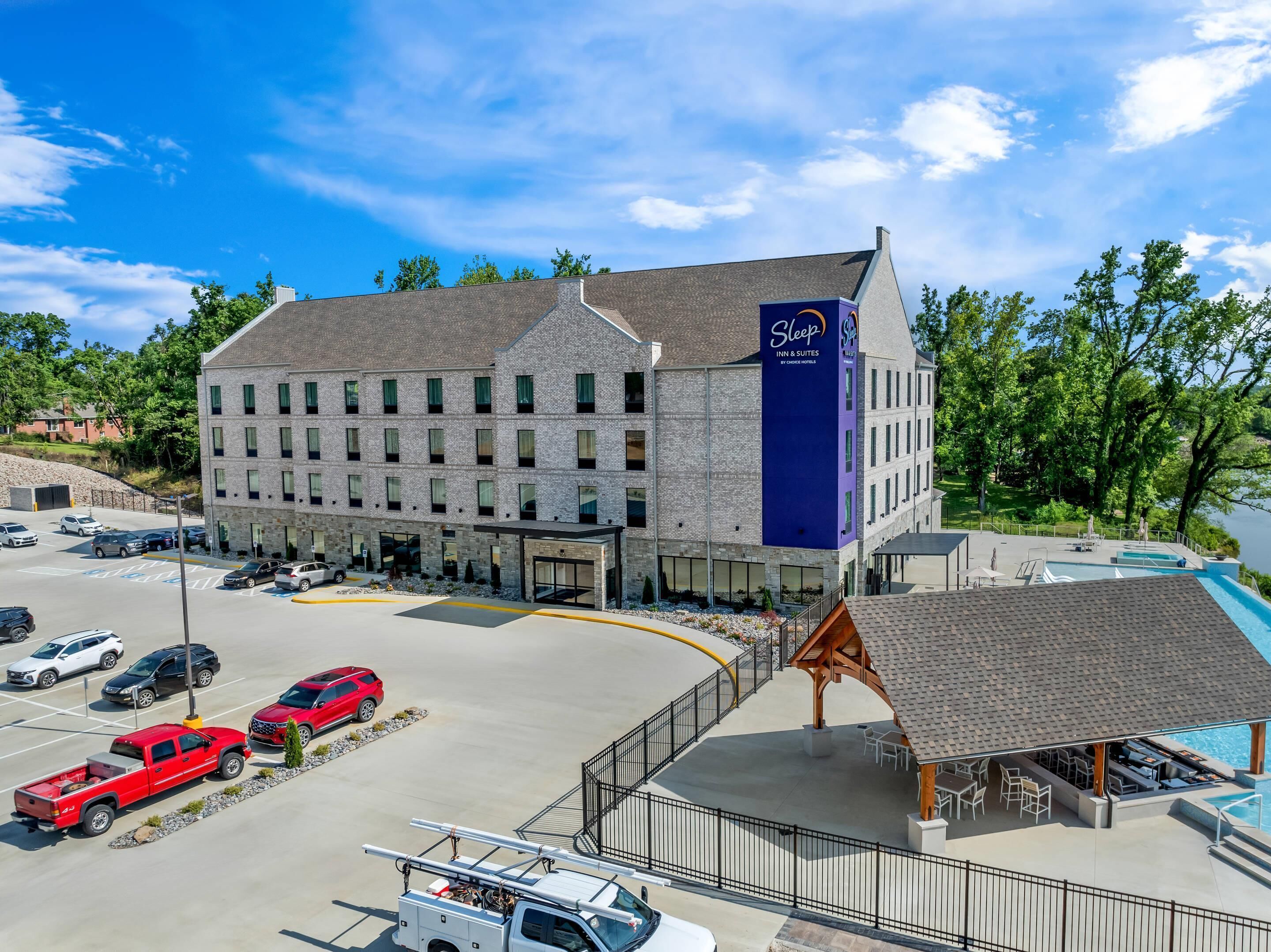 Ett Sleep Inn & Suites-hotell med en parkeringsplats, en pool och ett takförsett utomhusområde med sittplatser.