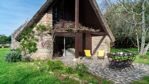Una casa in pietra con tetto di paglia, un patio con tavolo e sedie, e un'area giardino.