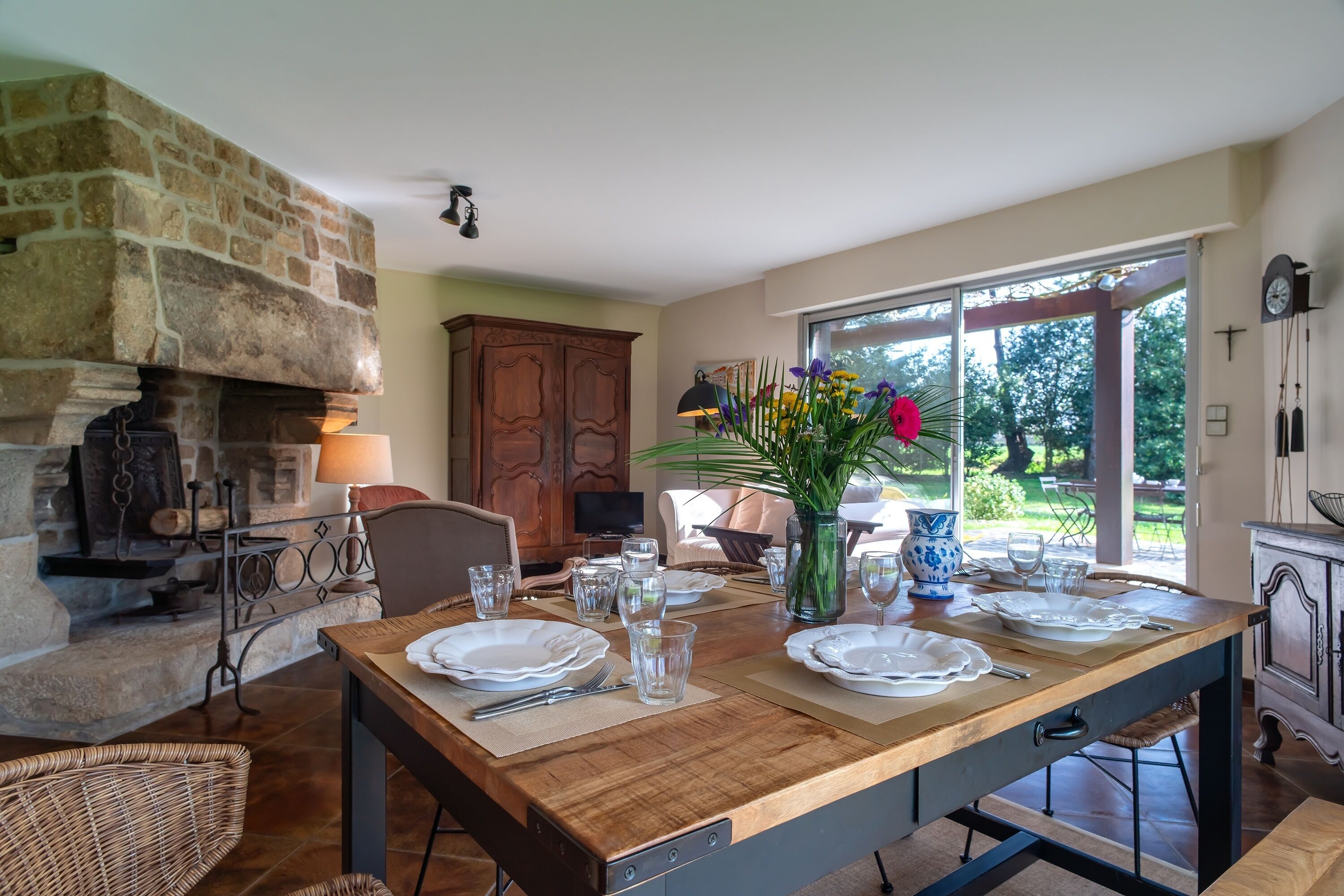 A dining area with a stone fireplace, wooden table, and chairs.