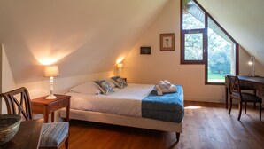 Una camera da letto con un letto, comodini, una scrivania, una sedia e una finestra vista.
