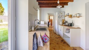 A kitchen with a wooden ceiling, a sink, a refrigerator, and a window. - Plomarch Pella - à 300m de la plage (Douarnenez)