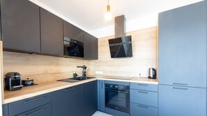 A modern kitchen with dark cabinets, a wooden countertop, a built-in oven, and a coffee machine. - L'Escale de Césarine - 1 km de la plage (Carnac)