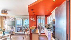 Cozinha moderna com uma ilha grande, eletrodomésticos de aço inoxidável e vista para o exterior.