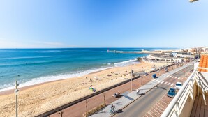 Vista costeira com praia, calçadão e edifícios.