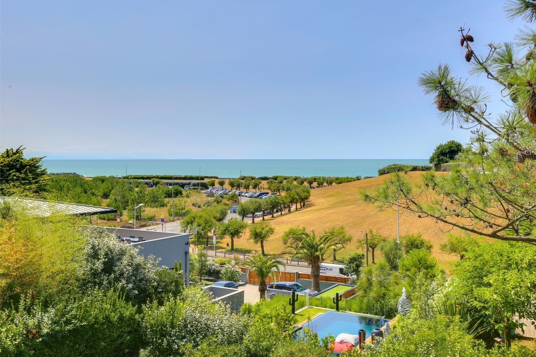 A resort with a pool, a parking area, and a view of the sea.