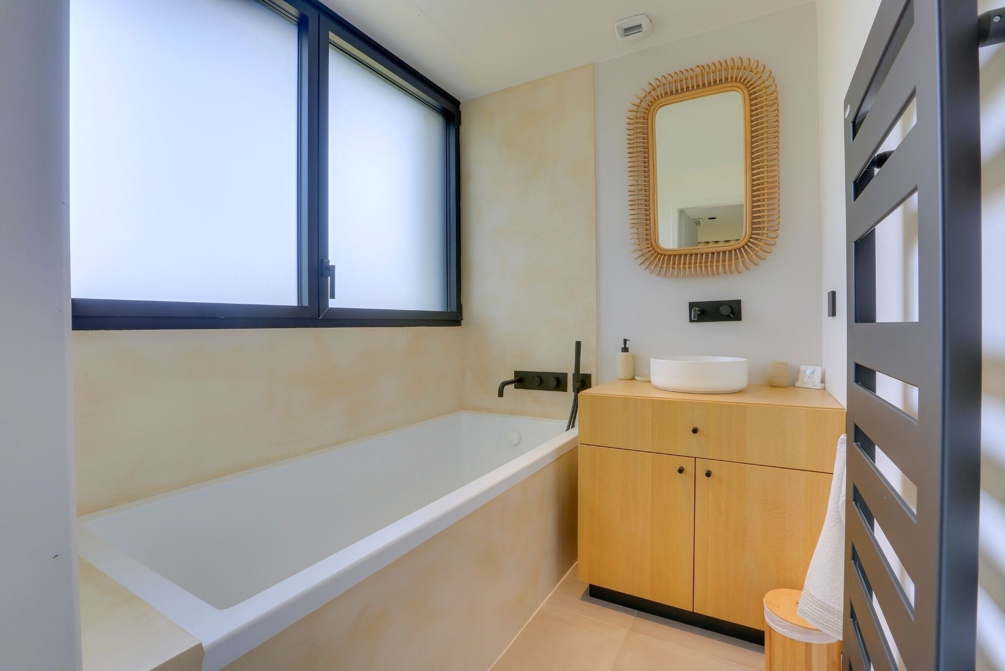 Ein modernes Badezimmer mit einer Badewanne, einem Holzwaschtisch und einem großen Spiegel.