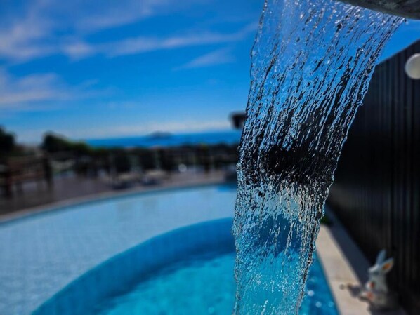 A pool with clear water and a visible water spout. - Pousada Bella Vista - Alto da Brava (Buzios)