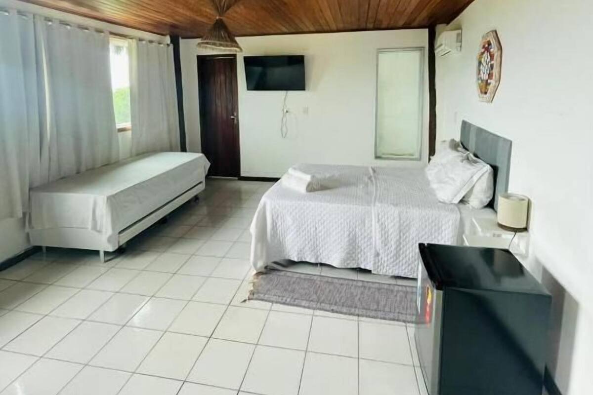 Une chambre à coucher avec un lit, un canapé, une télévision et un bureau.