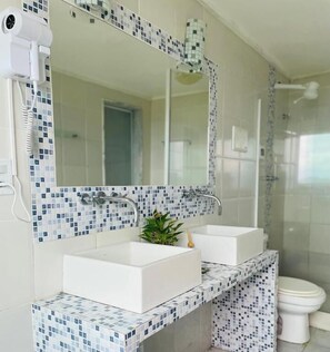 A bathroom with a white sink, a mirror, and a shower. - Pousada Bella Vista - Alto da Brava (Buzios)