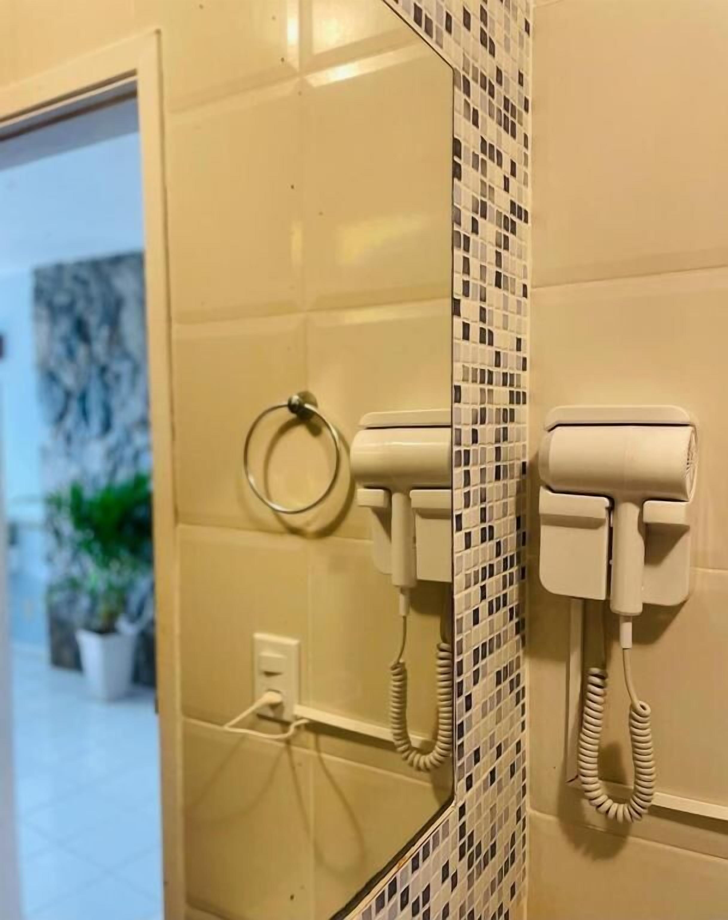 A bathroom with a mirror, two white telephone booths, and a tiled wall with a mosaic pattern.