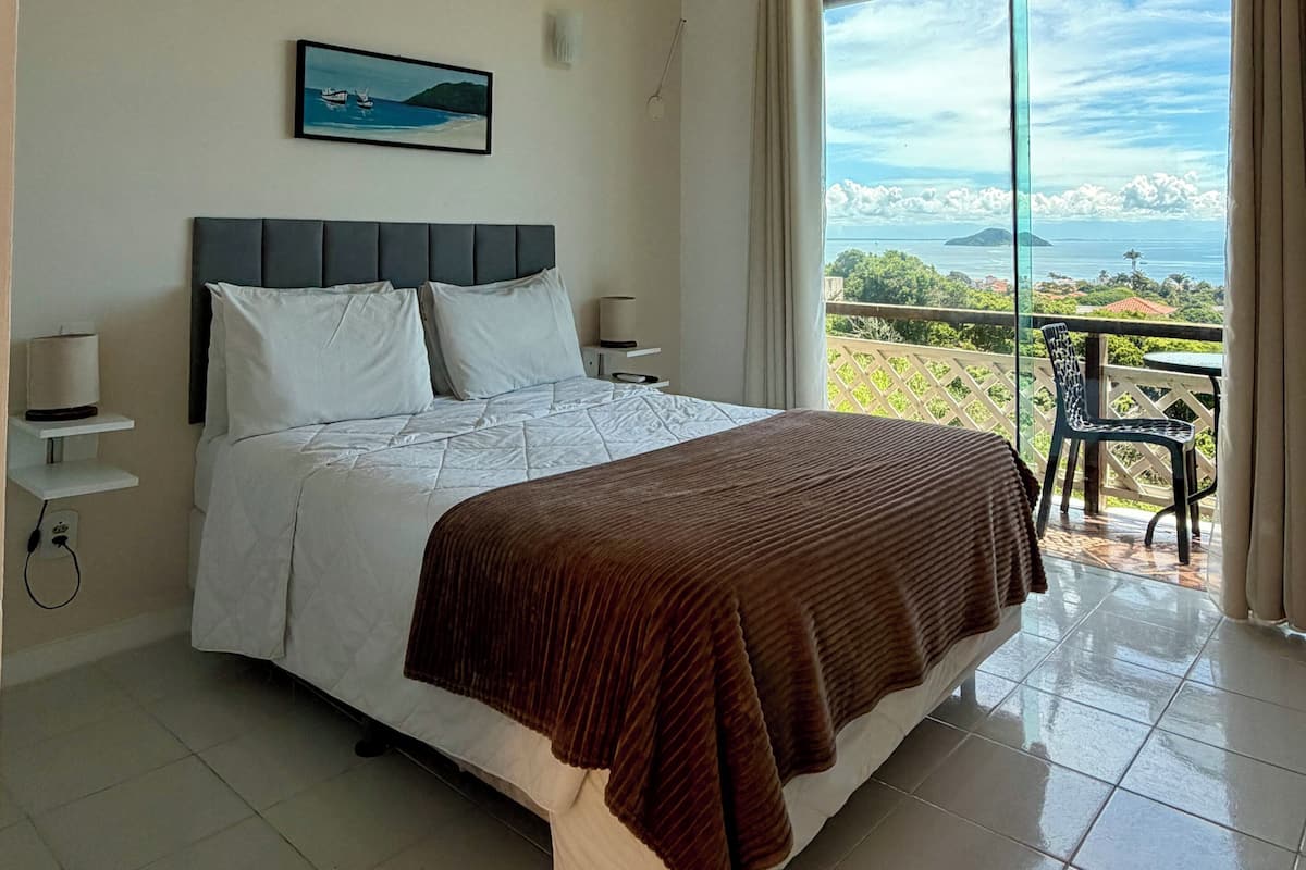 Une chambre à coucher avec un lit, un tableau, une table de chevet et une vue sur l’extérieur.