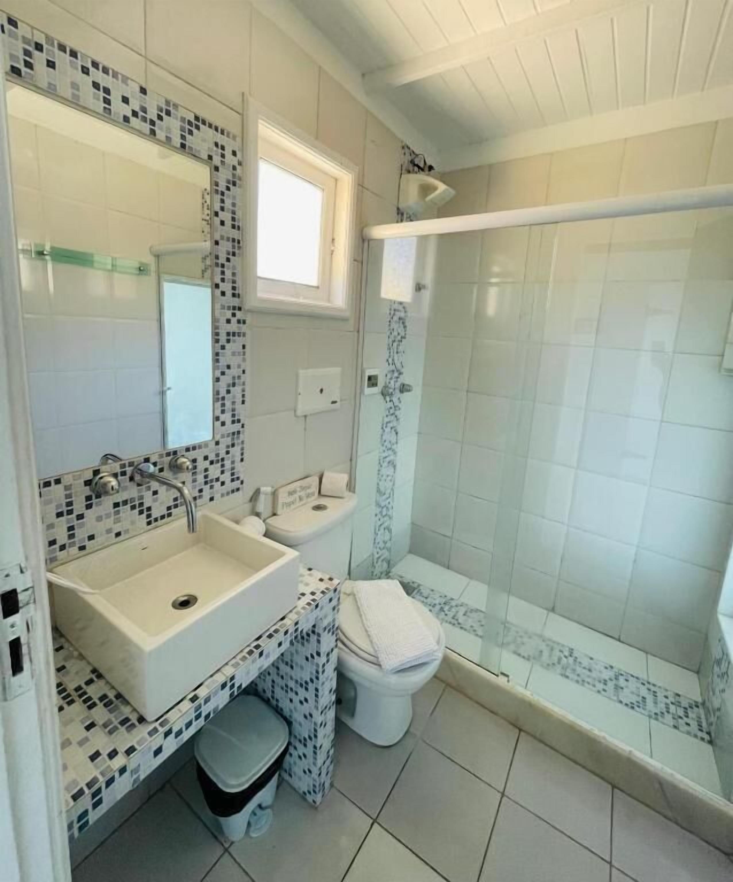 Un bany amb un lavabo, vàter i plat de dutxa blancs.