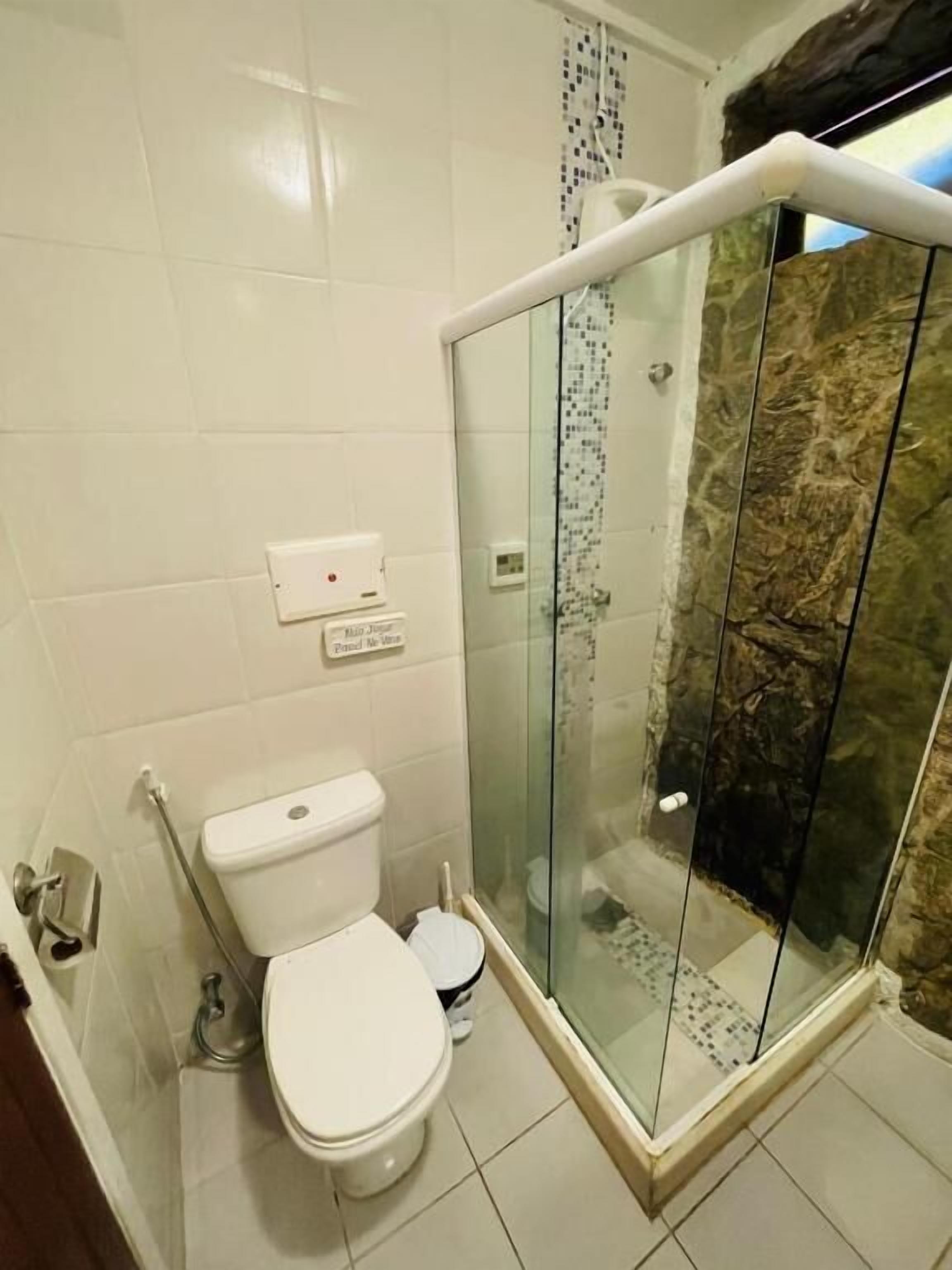 A bathroom with a toilet, a glass shower enclosure, and a tiled wall.