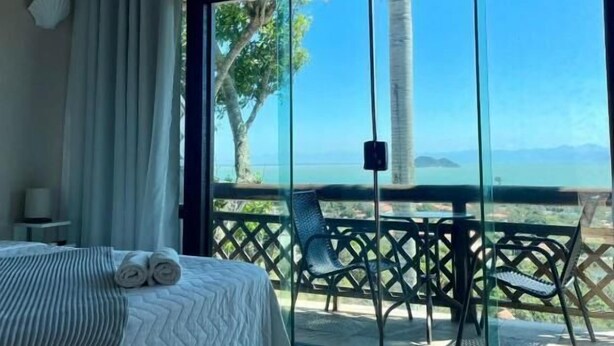 Ein Hotelzimmer mit Bett, Meerblick und einem Balkon mit Tisch und Stühlen.