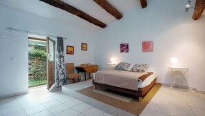 A bedroom with a bed, a desk, a chair, a lamp, and a view of the outdoors. - La Parenthèse de la Traverse - Avec piscine privée (Ferrières-Poussarou)