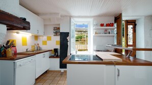 A compact kitchen with white cabinets, a wooden countertop, and a view to an outdoor area. - La Parenthèse de la Traverse - Avec piscine privée (Ferrières-Poussarou)