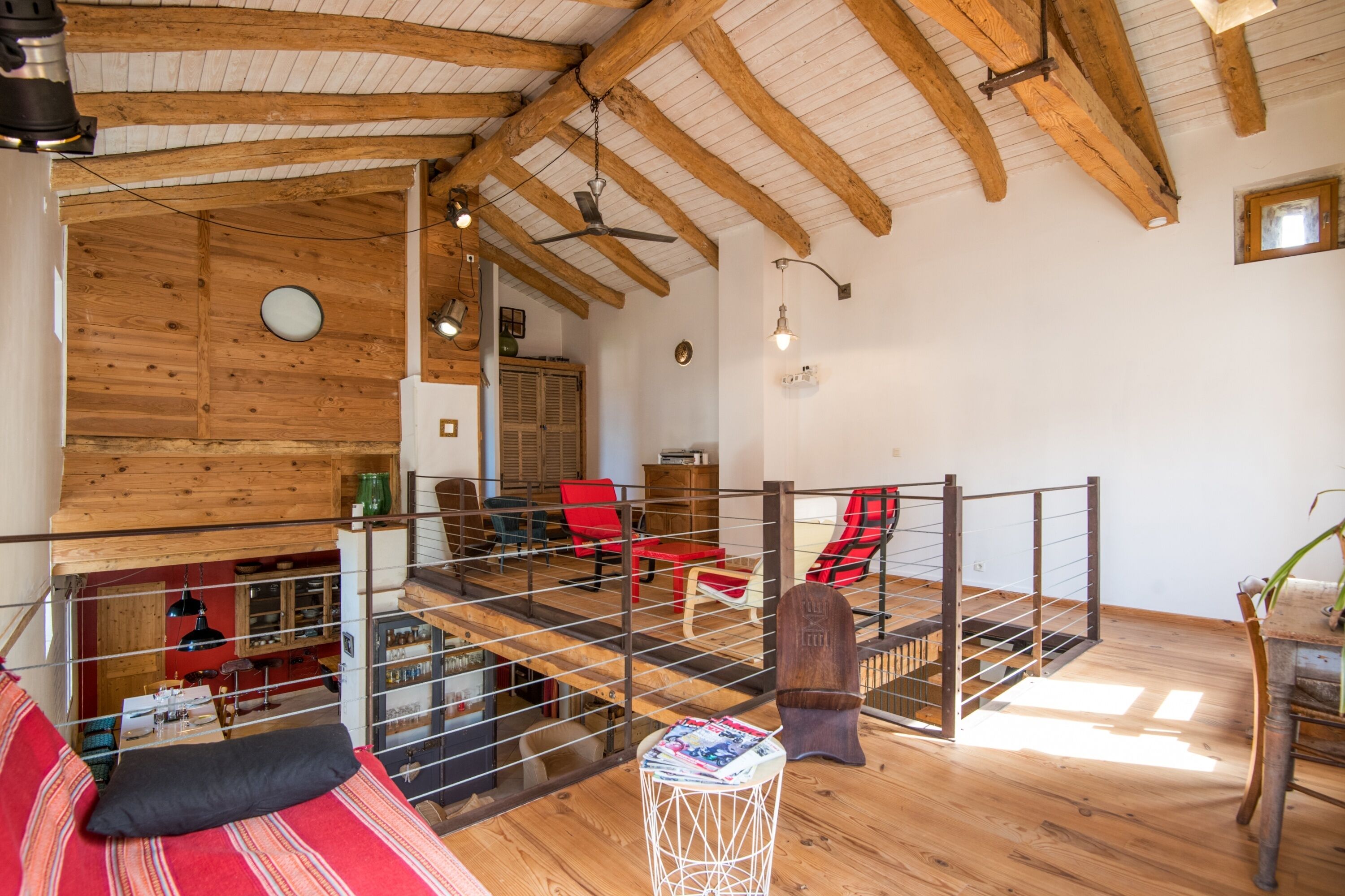 A rustic interior with wooden beams, a loft area, and a staircase.