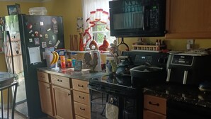 Una cocina con gabinetes de madera, microondas, refrigerador y estufa.
