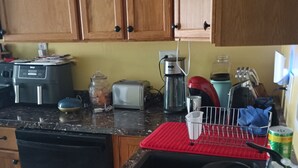 Una cocina con armarios de madera, lavavajillas, tostadora, cafetera y varios utensilios de cocina sobre la encimera.