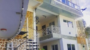A multi-story residential building with a staircase, balconies, and a small outdoor seating area. - Elicon Suites  (Baclayon)