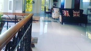 A spacious living area with a balcony, a sofa with British flags, and a dining area with a table and chairs. - Elicon Suites  (Baclayon)