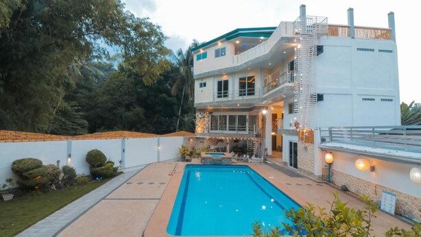 A two-story building with a swimming pool, outdoor lighting, and a staircase leading to the upper level. - Elicon Suites  (Baclayon)