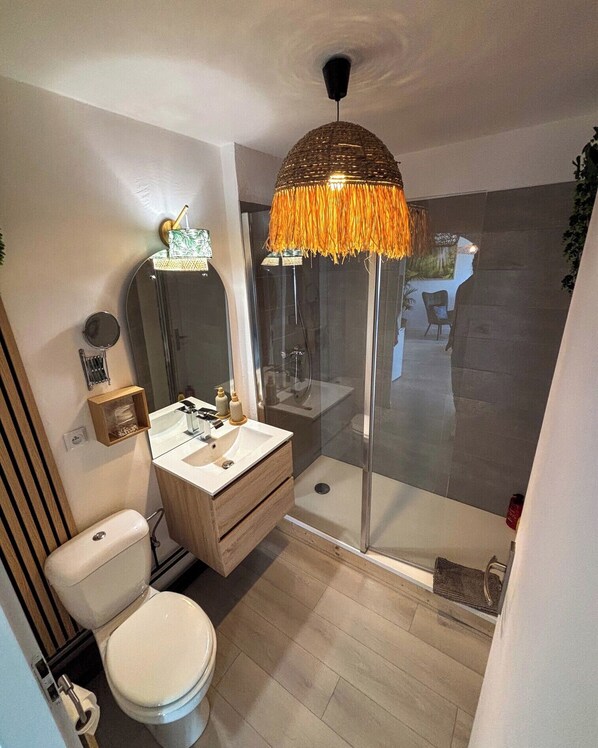 A modern bathroom with a toilet, sink, and glass shower enclosure.