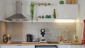 A kitchen with a coffee maker, kettle, and a small refrigerator.