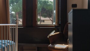 A room with a window, a chair, a crib, and a cabinet.