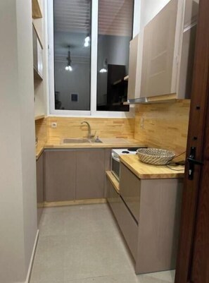 A compact kitchen with a sink, stove, and wooden countertop. - Gavrilis apartments: LOFT (Nenita)