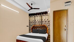 A bedroom with a bed, a ceiling fan, a door, and a wall-mounted air conditioner. - Super Hotel O Adarsh Nagar (Visakhapatnam)