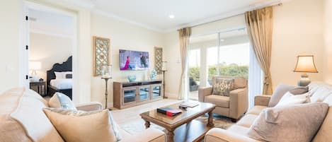 Un salón amplio con un sofá grande, una mesa de centro y un televisor montado en la pared.