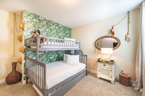 A bunk bed with a white headboard, a bedside table with a lamp, a mirror, and a small plant. - 6BR Home w/ Pool, Theater & Game Room (Kissimmee)