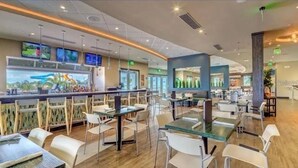 Een modern restaurant met een bar, verschillende zitplaatsen en grote ramen.